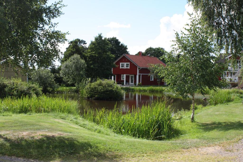 uma casa vermelha com um lago em frente a uma casa em Nolgårdens Turistboende em Ugglum
