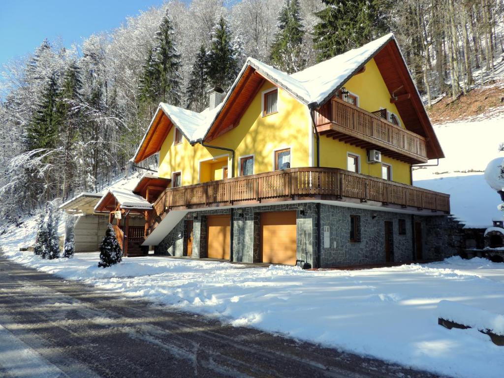 a house with a balcony in the snow at Apartments Gatej in Cerkno
