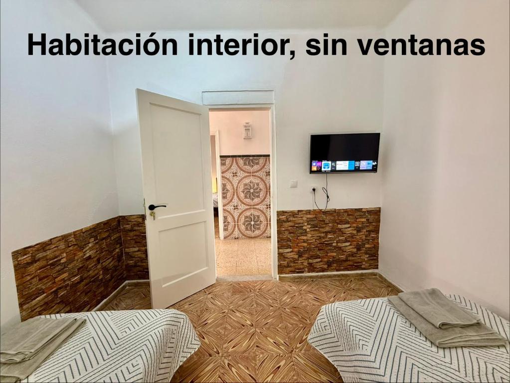 een kamer met twee bedden, een deur en een televisie bij Rooms La Laja 3 in Las Palmas de Gran Canaria