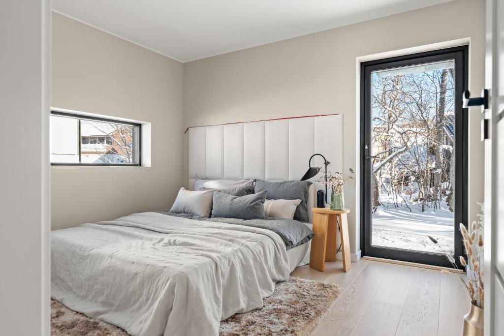 a white bedroom with a large bed and a window at Njord in Tromsø