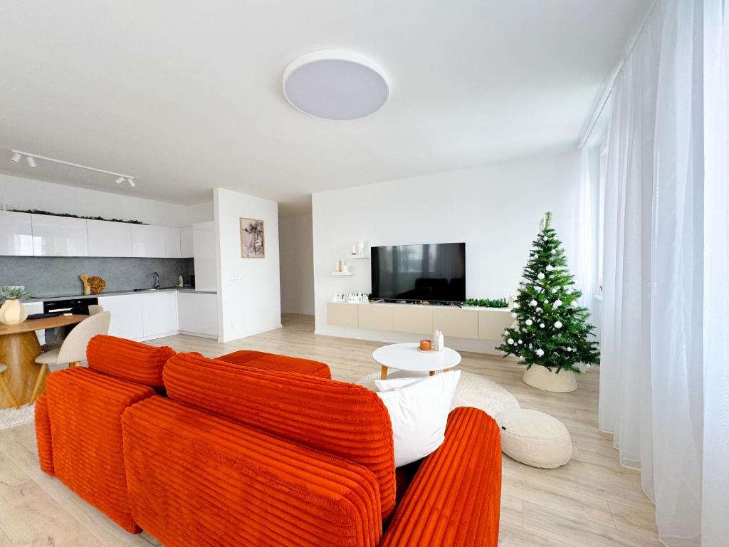 a living room with a orange couch and a christmas tree at A2 Severna Apartment, Luxury 88m2, Near City Center and High Tatras, Free Parking in Poprad