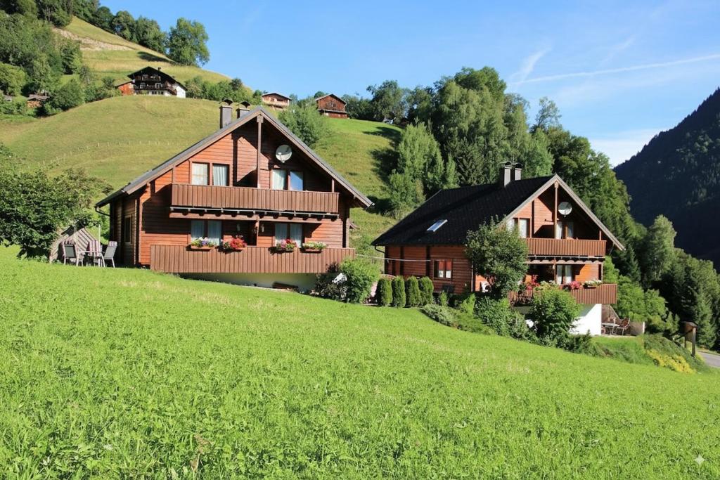 two wooden houses on a hill with a green field at Triberga Verwall in Sankt Gallenkirch