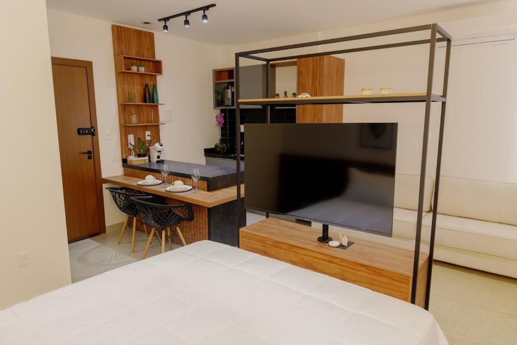 een slaapkamer met een grote flatscreen-tv in een kamer bij Studio completo, Piscina, Wi-Fi e Garagem in Três Corações