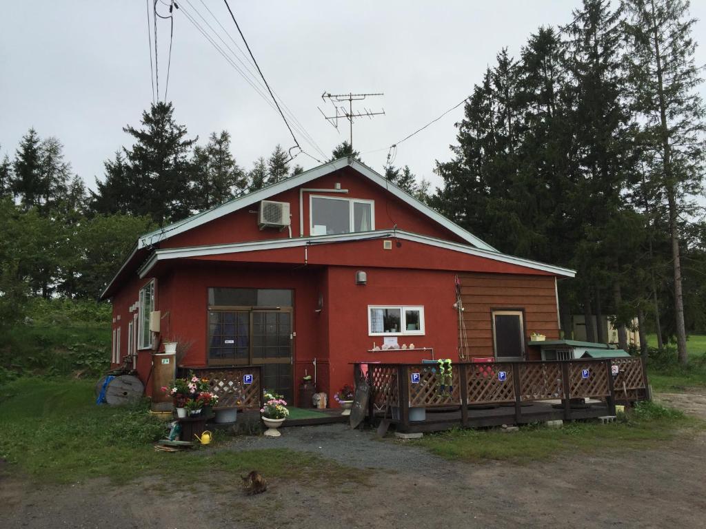 a red house with a porch and a yard at Farm&Inn Imodango Mura in Abashiri