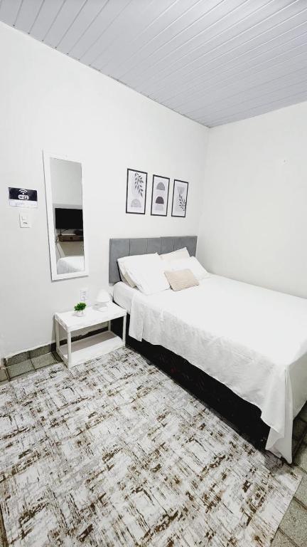 a white bedroom with two beds and a rug at Sao Luis Praia Studio in São Luís