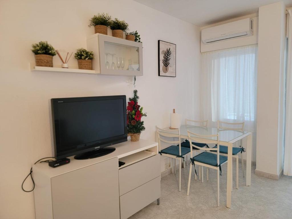 ein Wohnzimmer mit Fernseher und Tisch mit Stühlen in der Unterkunft Aguila Relax Apartment in Benalmádena