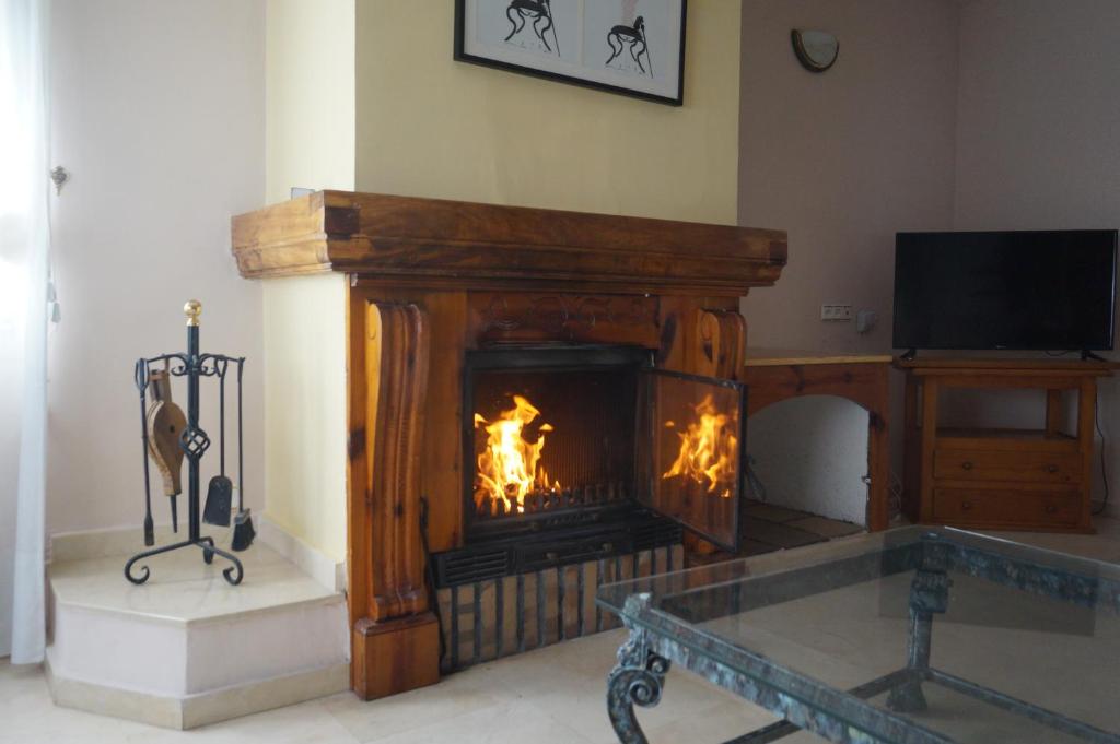 a living room with a fireplace and a tv at Cuencaloft Casa Rural Lagunas de Arcas in Arcas