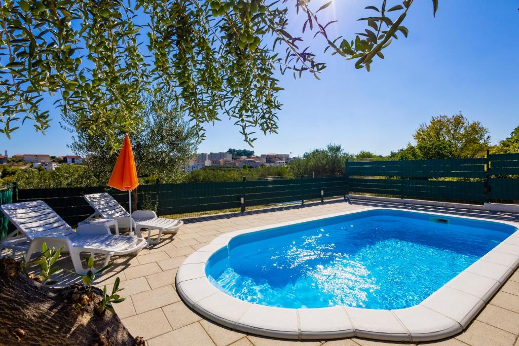 a swimming pool with two chairs and an umbrella at Holiday House Olive in Solin