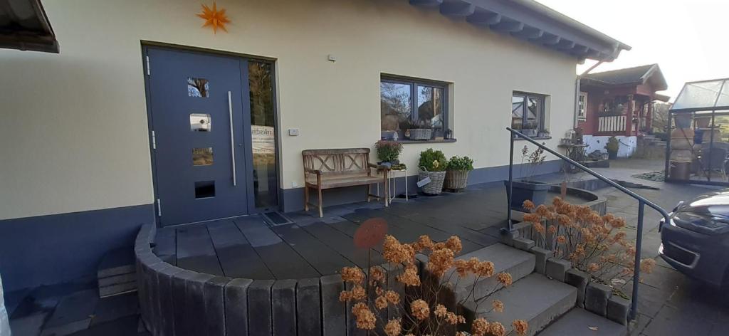 una veranda anteriore di una casa con porta blu di Gästehaus Hähnchenbach a Kelberg