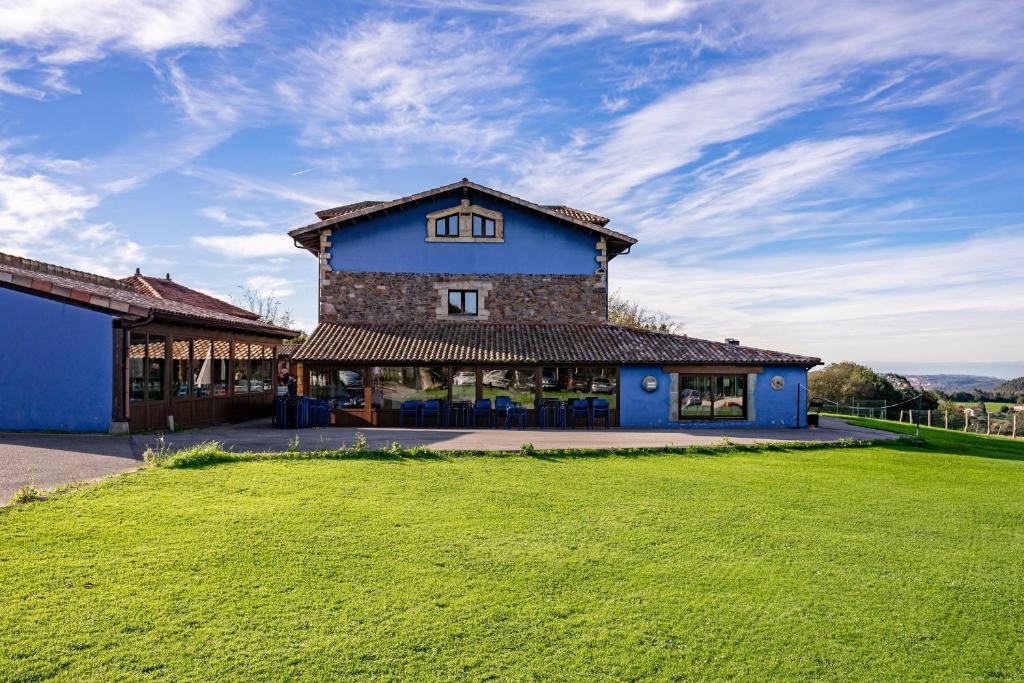 a blue building with a green field in front of it at Casona Asturiana Los Gamonales in Logrezana