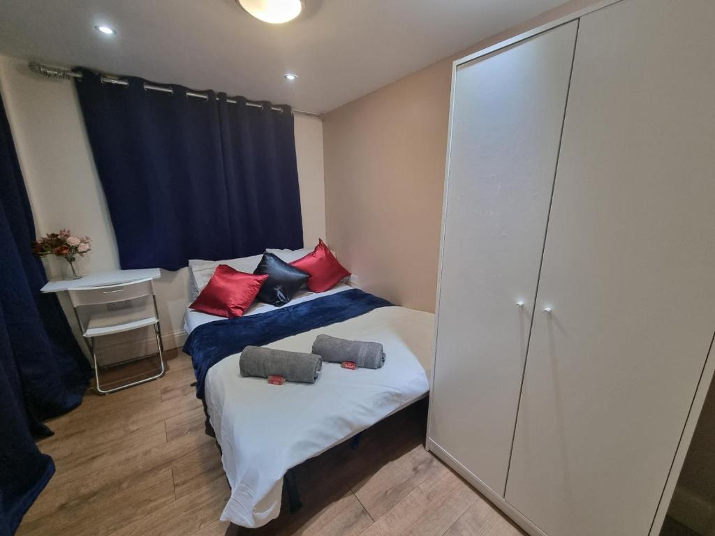 a bedroom with two beds with red and black pillows at 2 bedroom Flat Heathrow in Feltham