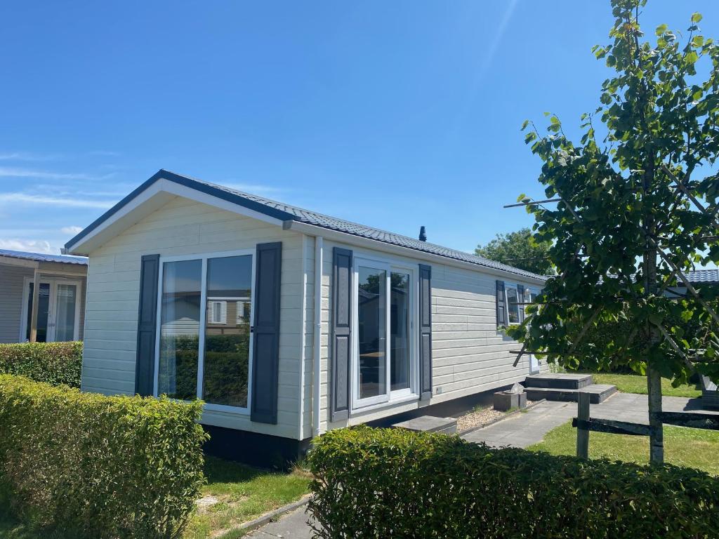 a small white house with large windows in a yard at Ferien-Chalet Oostkapelle in Oostkapelle