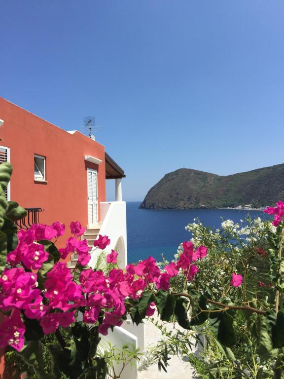 einen Blick auf das Meer von einem Haus mit rosa Blumen in der Unterkunft Villa Vista Mare Mela in Lipari