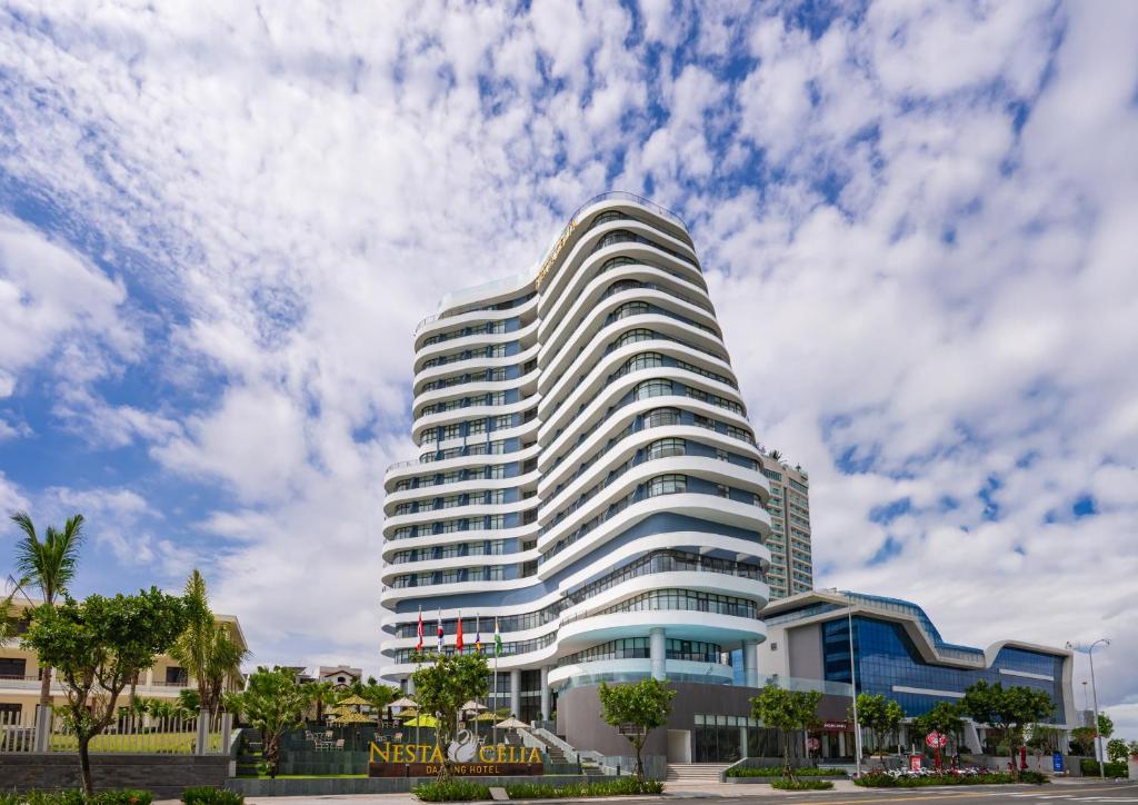 岘港Nesta Celia Danang Hotel的一栋高大的白色建筑，背景是多云的天空