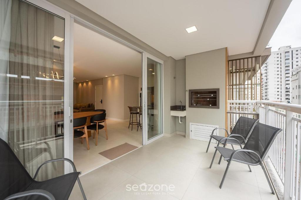 a balcony with chairs and a table and a dining room at Apto c/ Churrasqueira a 500m da Praia TDF0302 in Itapema