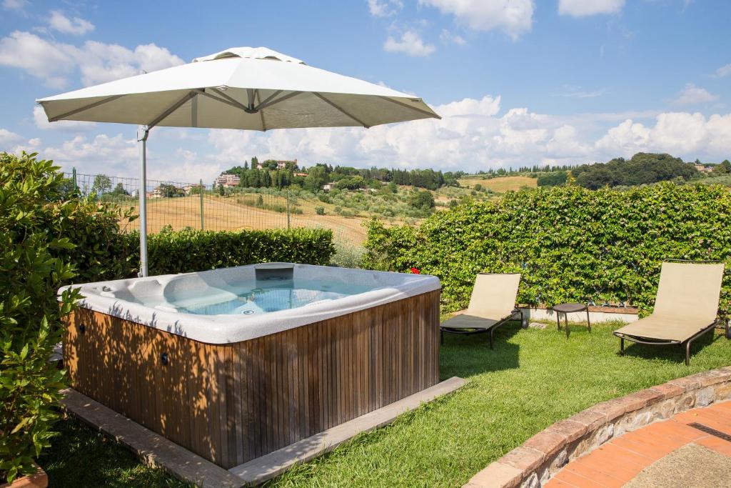 a hot tub with an umbrella and two chairs at Antica Fonte Residenza di Siena in Siena