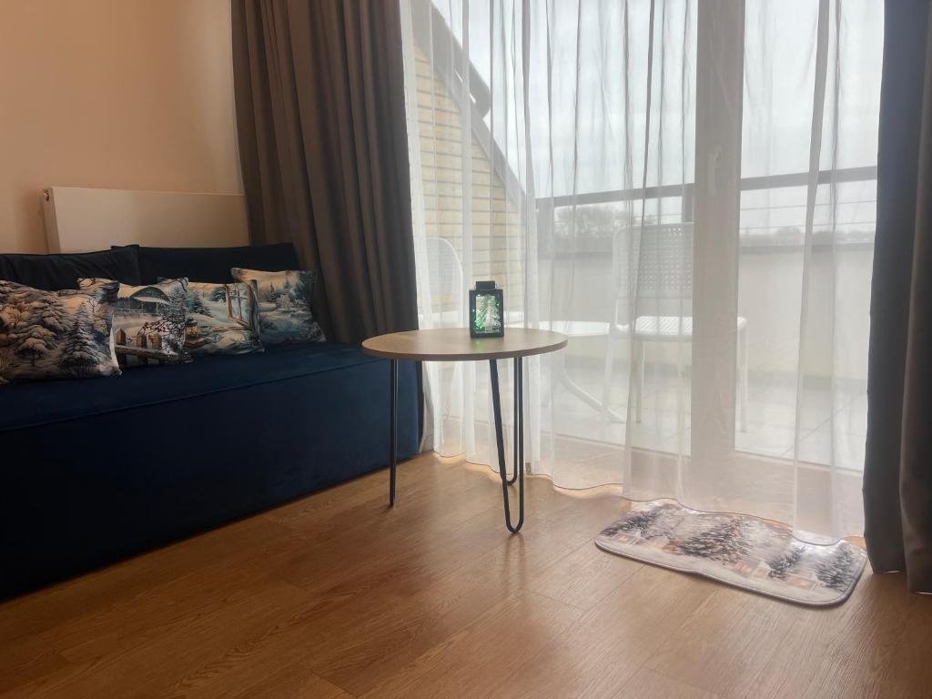 a room with a table and a couch and a window at Apartament Niebieski Centrum Sarbinowo w budynku z restauracją in Sarbinowo
