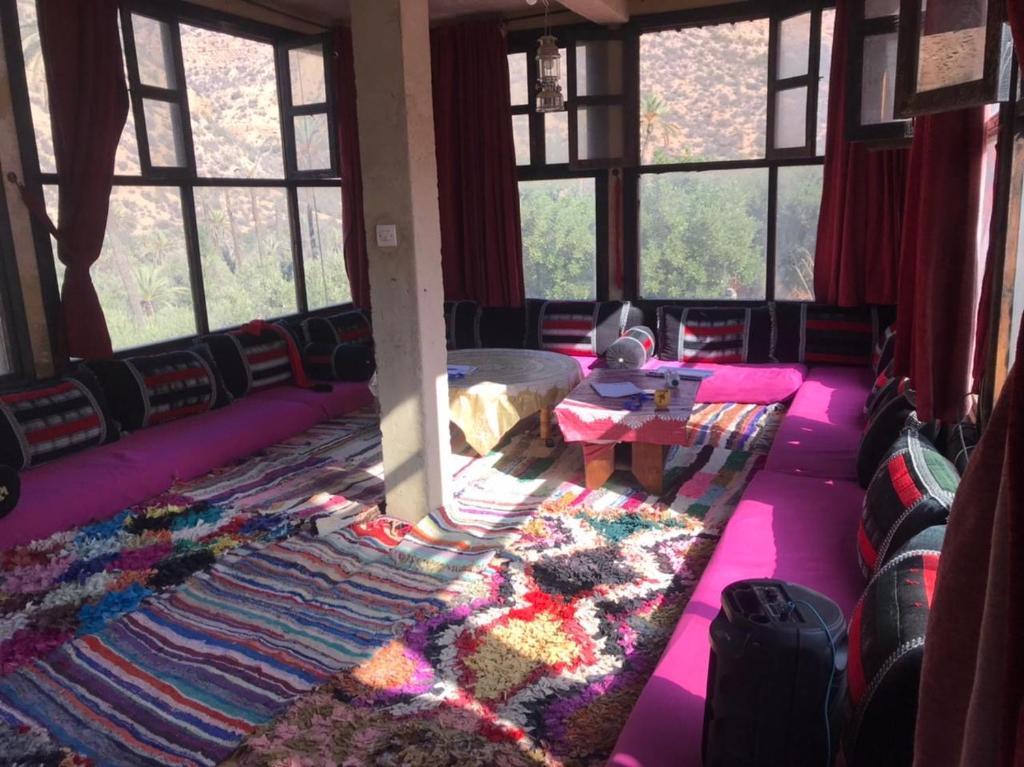 ein Zimmer mit einem Teppich und einem Tisch und Fenstern in der Unterkunft Auberge jawahir aguerd 