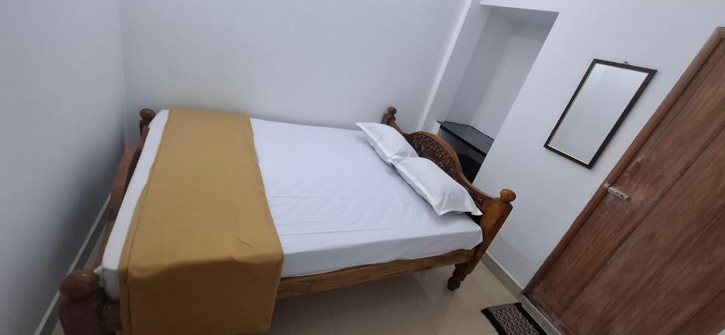 a small bed in a room with a mirror at Ashwin Home Stay in Tiruvannāmalai
