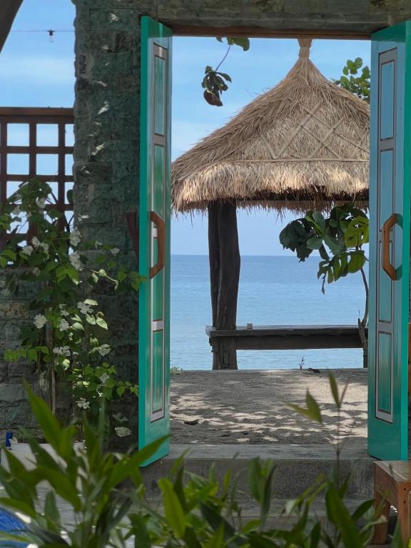 an open door to the beach with a straw umbrella at Tasola Boutique Hotel in Sorongjukung