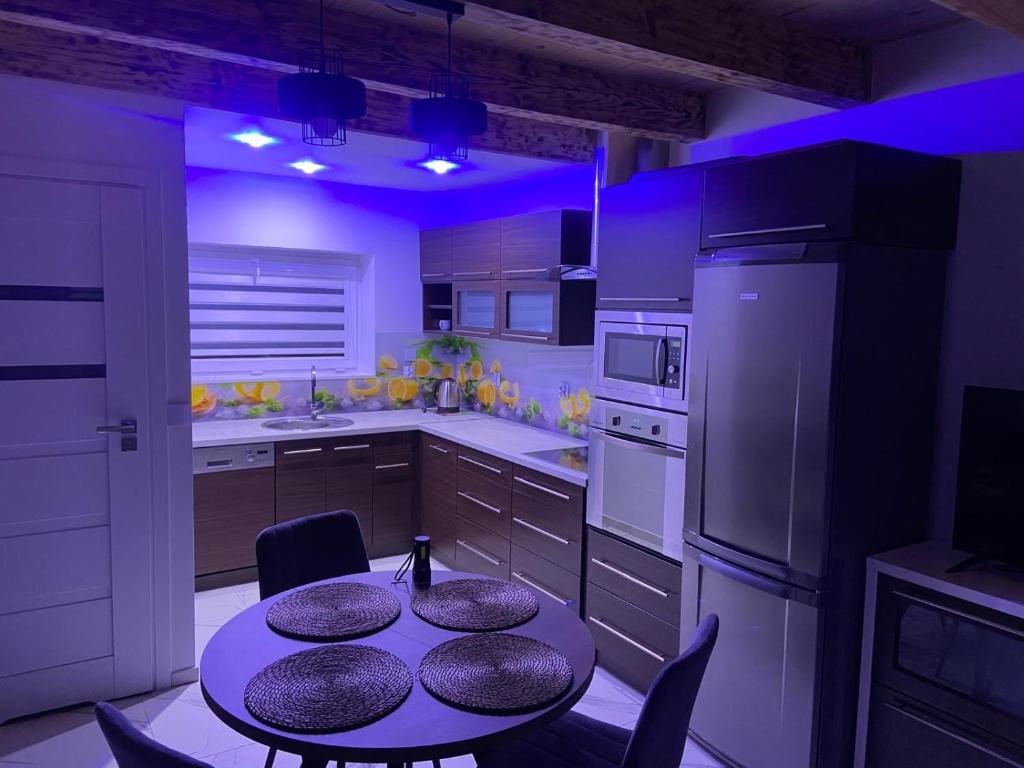 a kitchen with a table with chairs and a purple lighting at Apartament na lipowej in Pastwiska