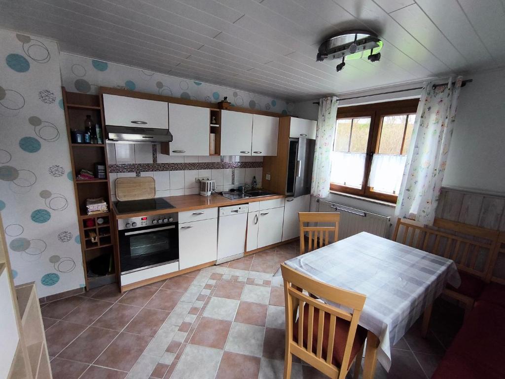 een keuken met witte kasten en een tafel met stoelen bij Ferienwohnung Angelika Zimmermann Dettelbach in Dettelbach
