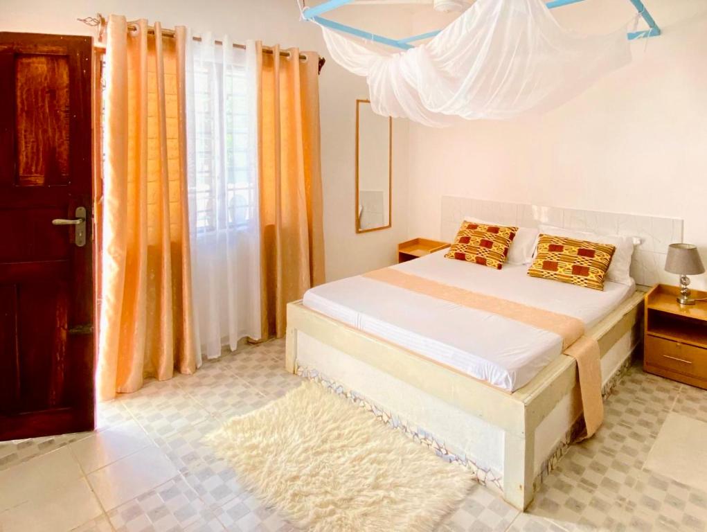een slaapkamer met een bed en een raam met oranje gordijnen bij Elala Studio Homes in Diani Beach