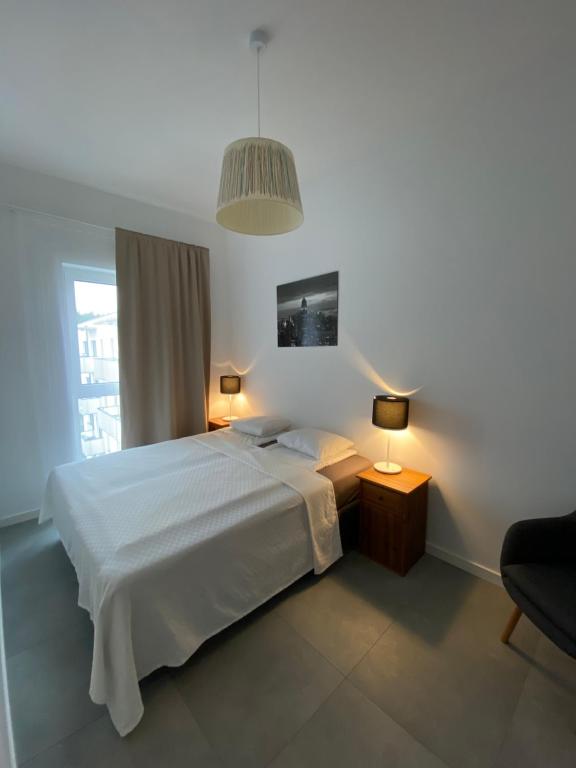 una camera da letto con un letto bianco e una lampada a sospensione di Apartament Kołobrzeska 2 a Piła