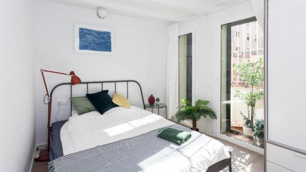 une chambre blanche avec un lit et une fenêtre dans l'établissement Ramblas Apartment Central BCN, à Barcelone