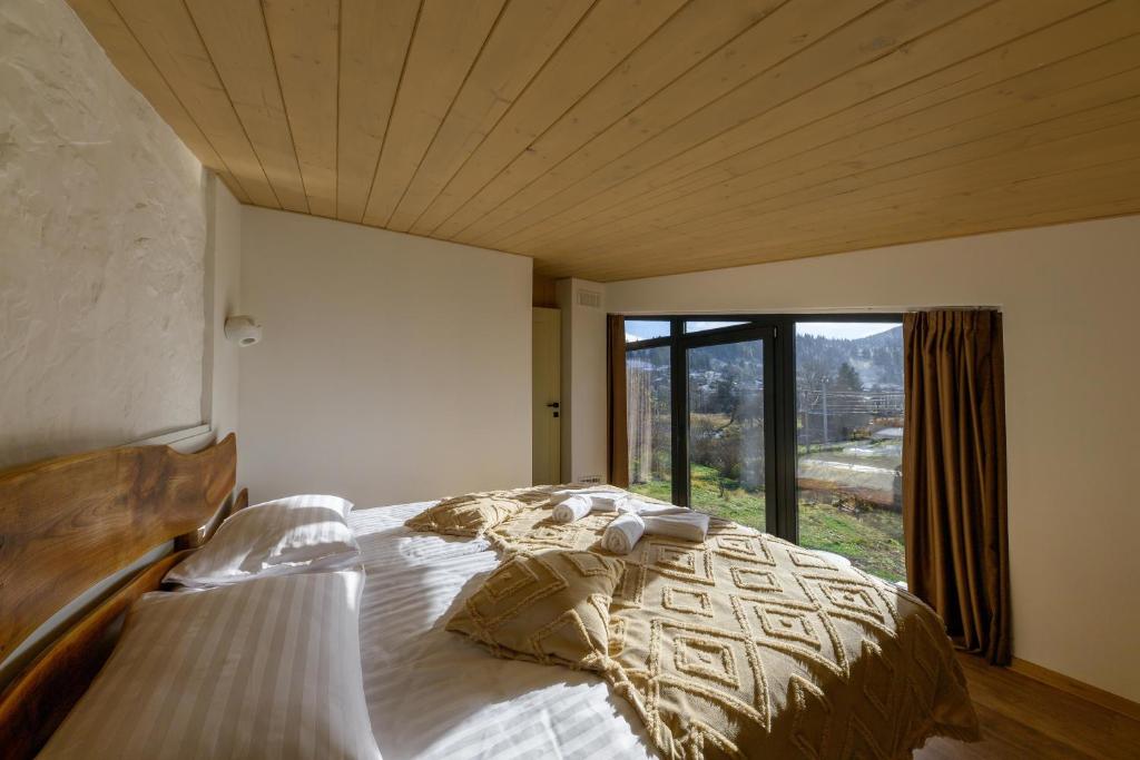 a bedroom with a large bed with a large window at Domivka котедж із чаном-джакузі, каміном і кіно-зоною у Cлавську in Slavske