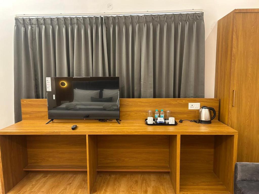 telewizor siedzący na drewnianym biurku w obiekcie 69th Heaven Hotel w mieście Devanhalli