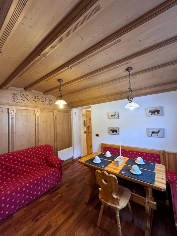 a living room with a table and a red couch at Apartament Doge in Sappada