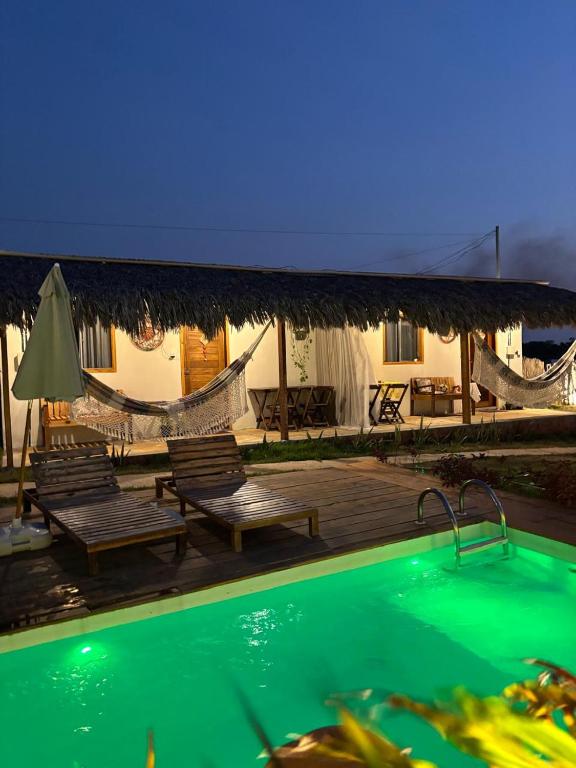 a resort with a swimming pool and chairs and a house at Vila Orun Pousada in Barreirinhas