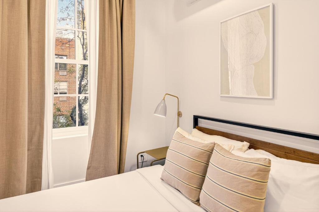 a bedroom with a white bed with a window at Outsite Chelsea in New York