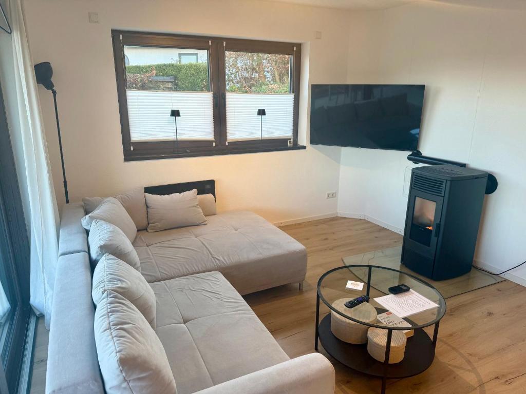 a living room with a couch and a tv at Ferienwohnung Auszeit am Waldrand in Olpe
