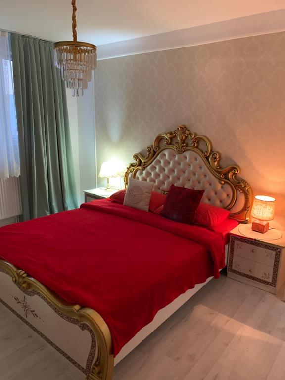 Un dormitorio con una cama grande con sábanas rojas y una lámpara de araña. en Slatina Cornisiei apartament central 2 camere și living, en Slatina
