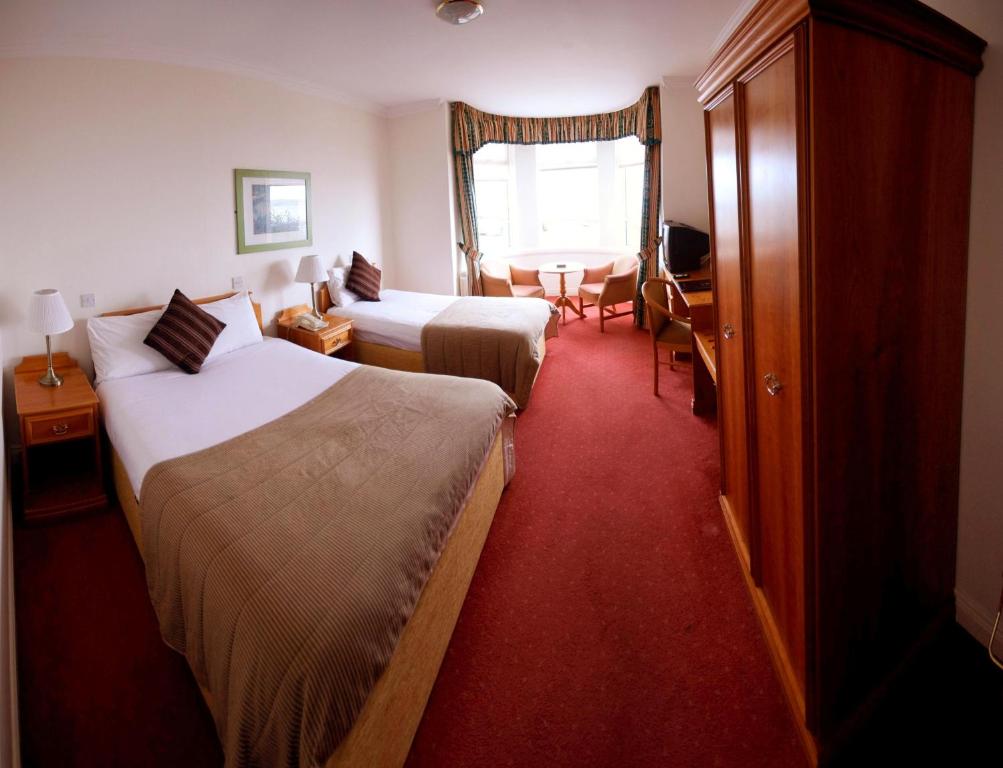 una camera d'albergo con due letti e un tavolo di White Sands Hotel a Portmarnock