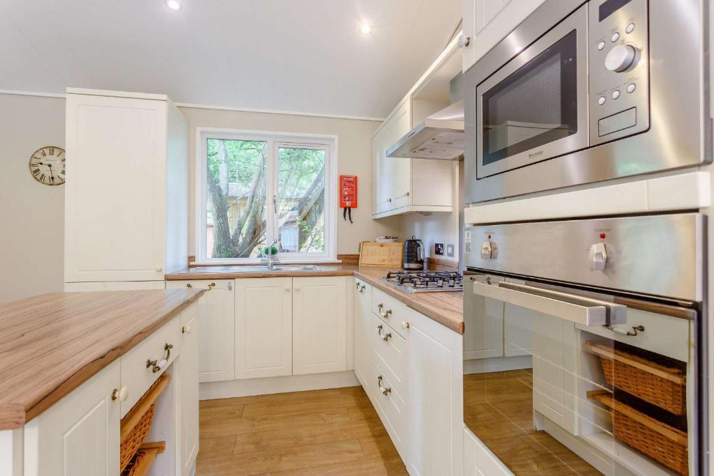 Una cocina con gabinetes blancos y un microondas. en Cupid Lodge, en Kingham