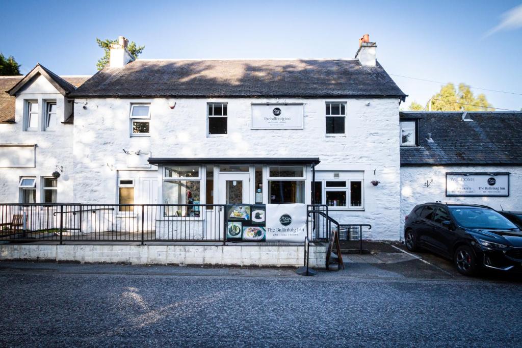 een wit gebouw met een auto ervoor geparkeerd bij The Ballinluig Inn in Pitlochry