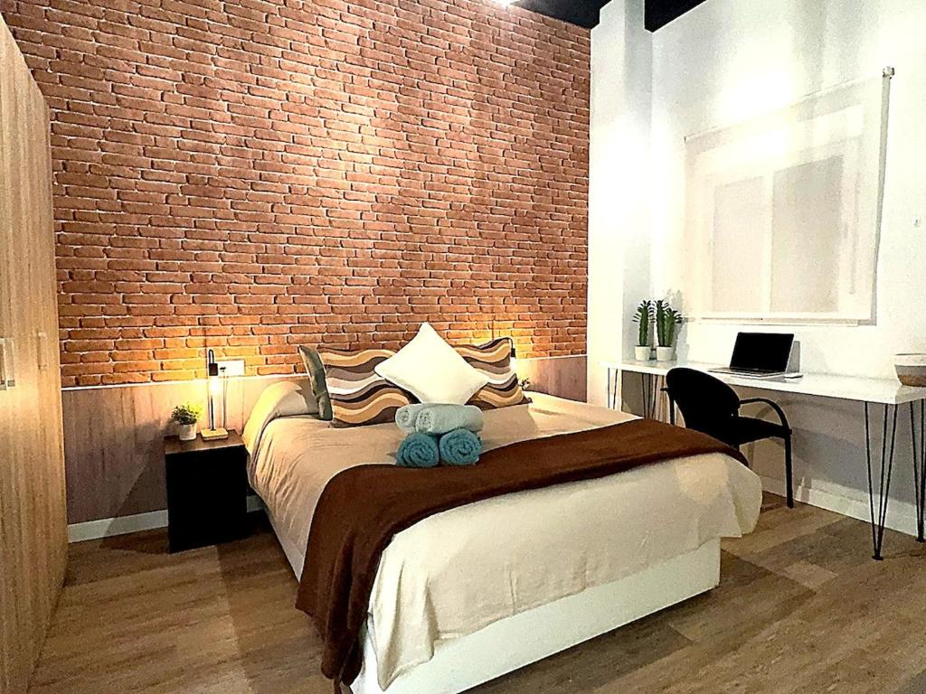 a bedroom with a large bed with a brick wall at Apartmento Ópalo in Seville