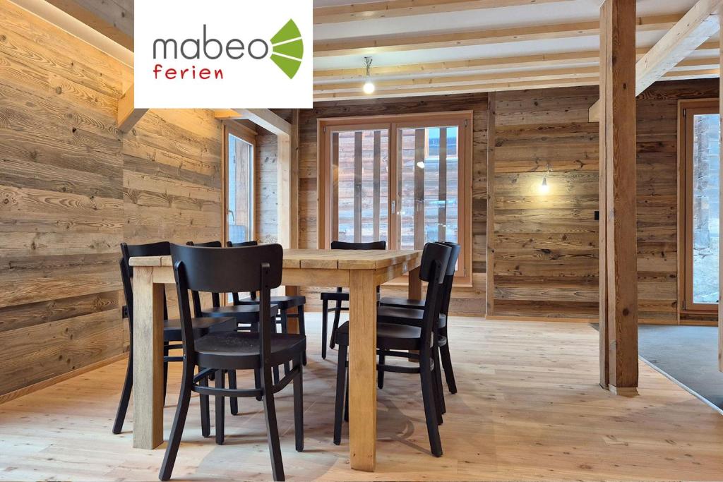 einen Tisch und Stühle in einem Zimmer mit Holzwänden in der Unterkunft Stadel Alpenstern mit Wellnessbereich in Blitzingen