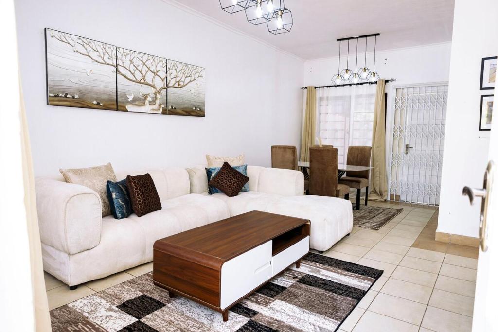 un soggiorno con un divano bianco e un tavolo di Metris Foxdale Apartments a Lusaka
