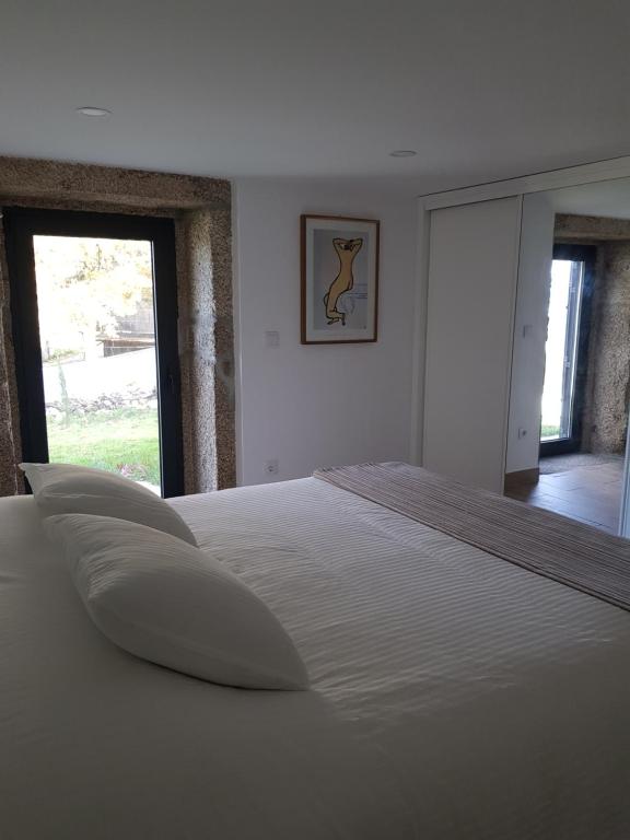 ein großes weißes Bett in einem Schlafzimmer mit Fenster in der Unterkunft Quinta dos Carvalhos in Cabana Maior