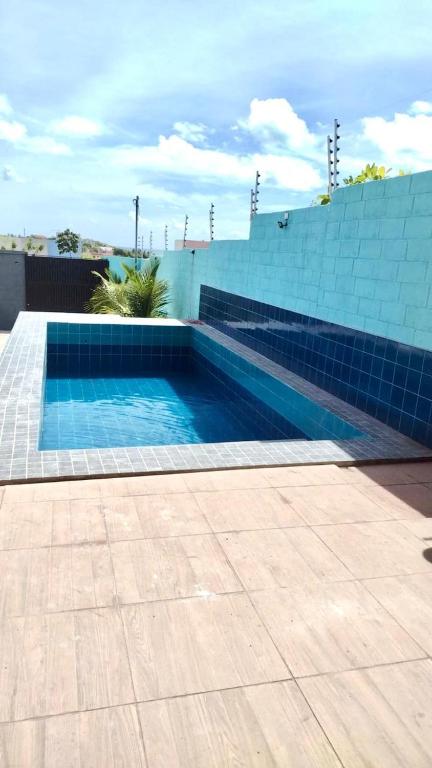 a swimming pool next to a blue tile wall at Flat LITORAL SUL PB CARAPIBUS in Conde