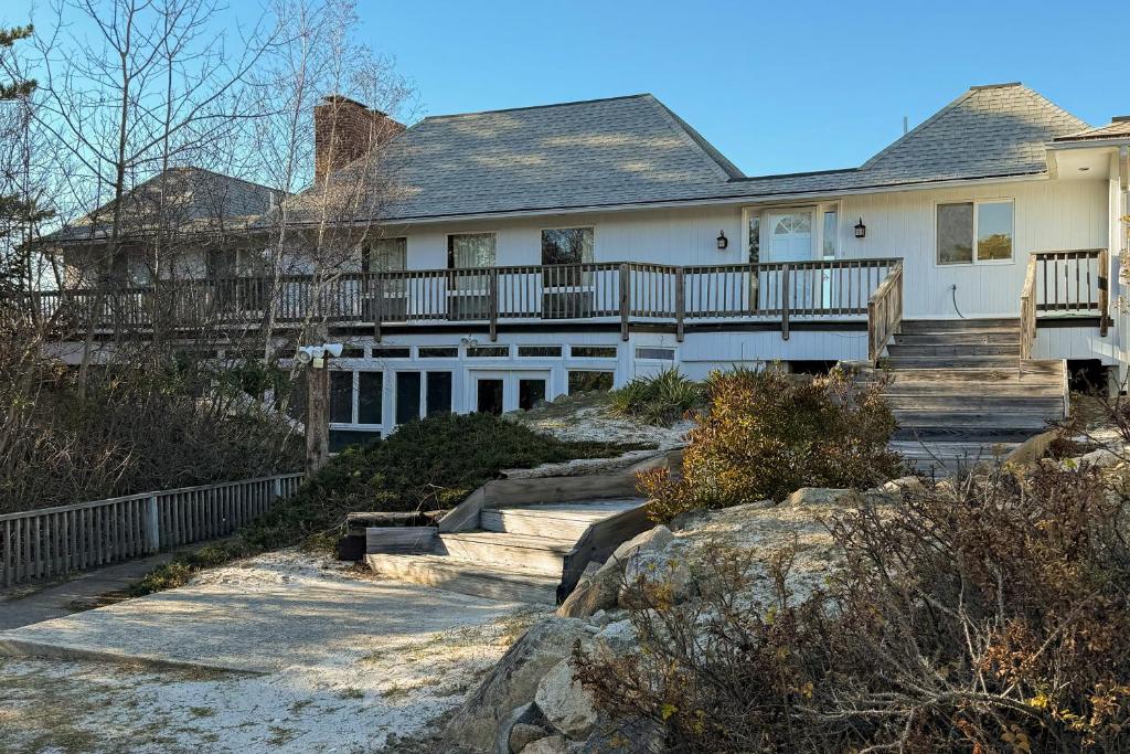 een wit huis met een veranda en een trap bij La Casa De La Playa in Lanesville