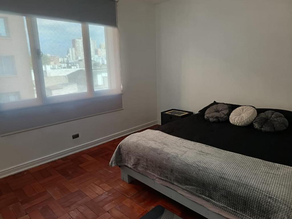 a bedroom with a bed with two pillows and a window at GuestHouse Habitaciones SANTIAGO CENTRO in Santiago