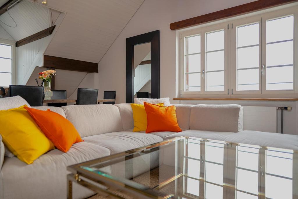 sala de estar con sofá blanco con almohadas de color naranja y amarillo en Lakefront Grand Residence, en Ligerz