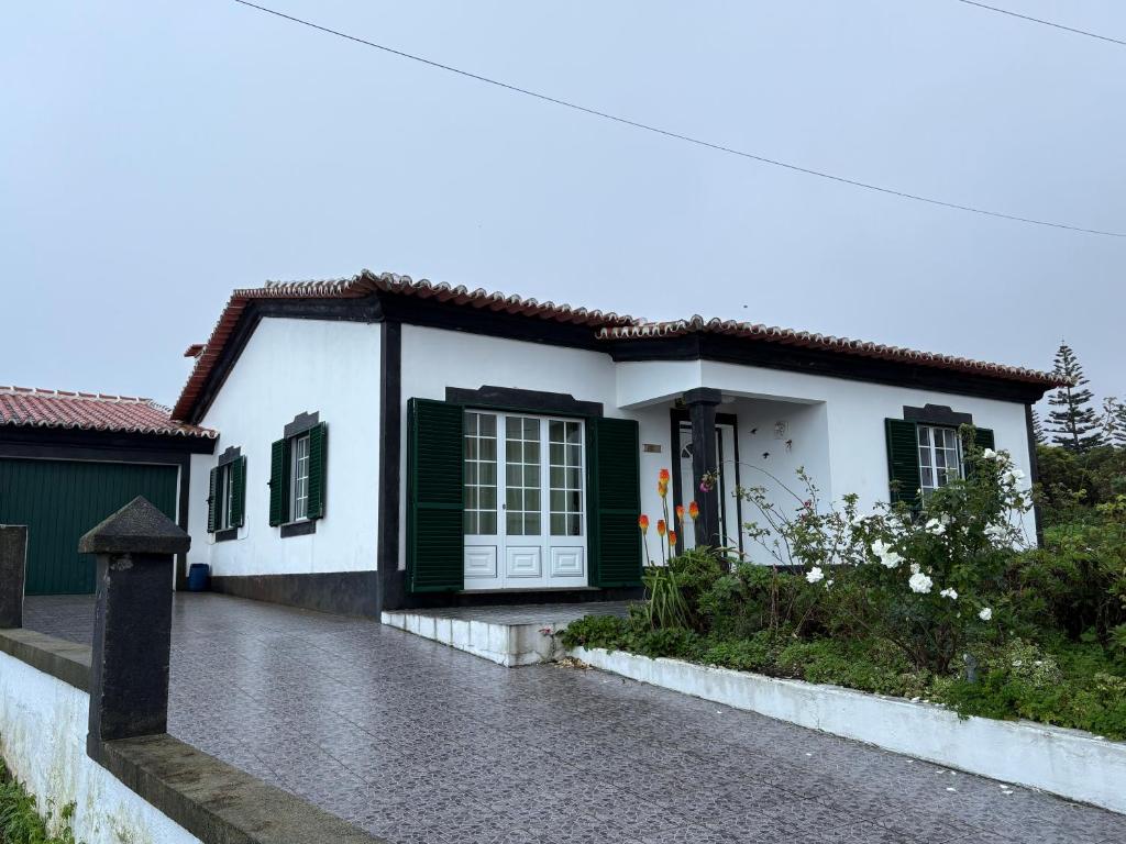 a white house with green shutters and a driveway at Zizi home in Biscoitos