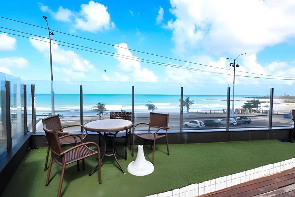 einen Balkon mit einem Tisch und Stühlen sowie Strandblick in der Unterkunft Cobertura duplex de frente pro mar in Natal