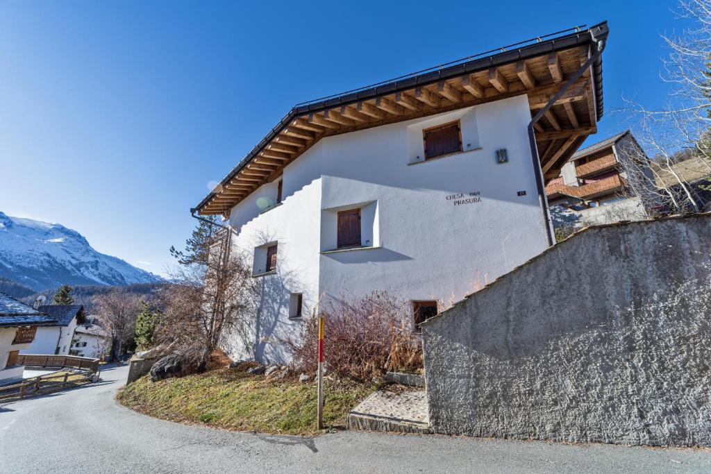 een wit gebouw met een houten dak op een straat bij Chesa Prasura - Celerina in Celerina